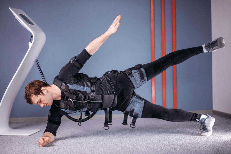 Athlete in an EMS suit performing a side plank exercise, connected to a device through cables.